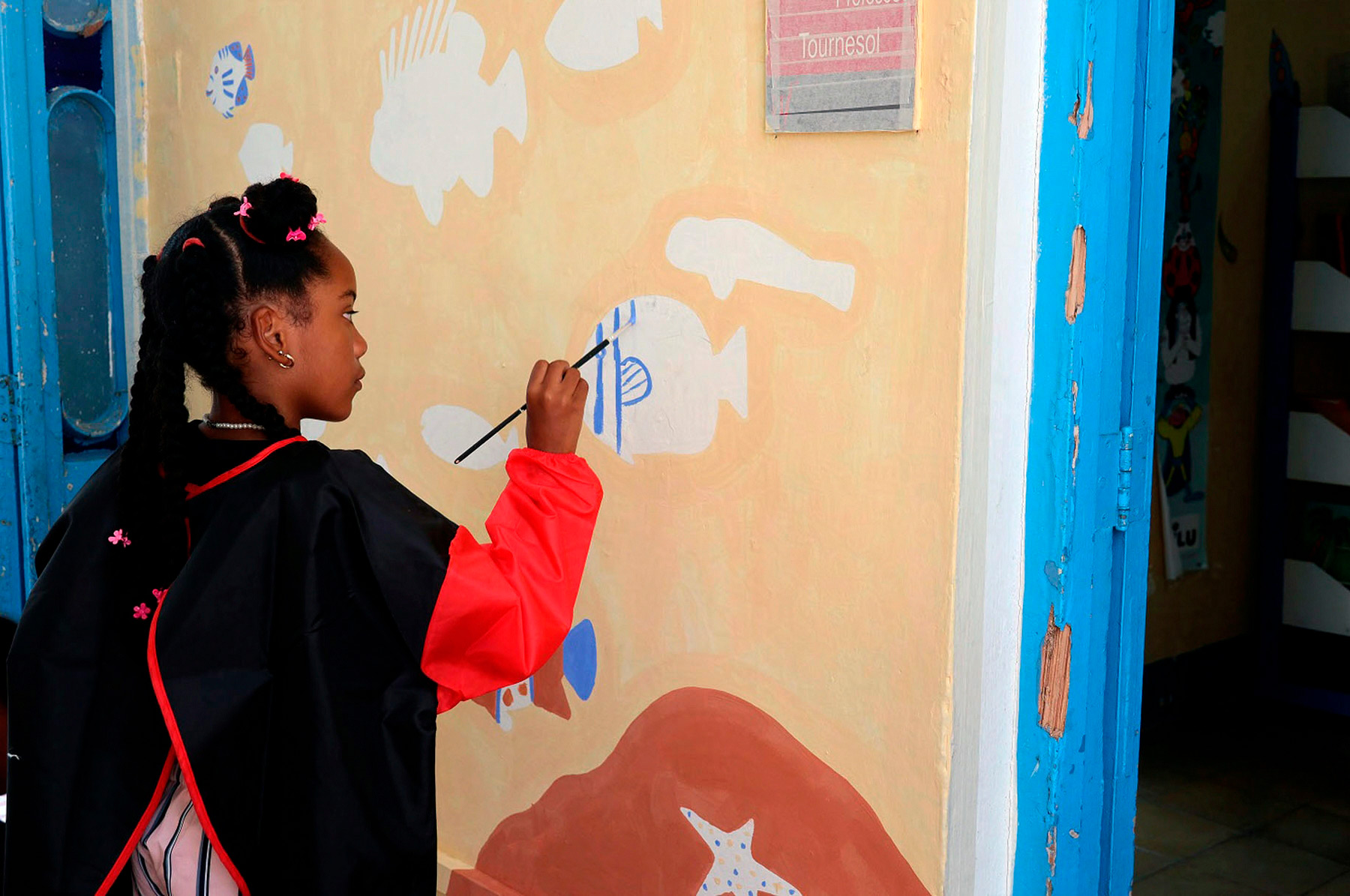 enfant qui peint sur la fresque murale de l'Alliance français de Cuba