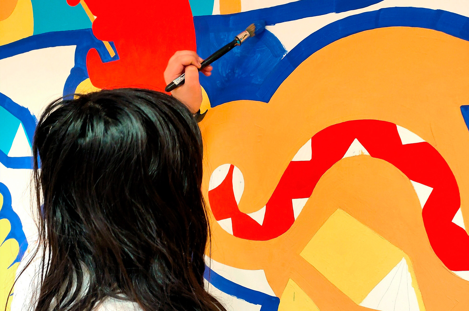 enfant qui peint une fresque murale participative dans l'espace jeunesse de la médiathèque de Marlenheim